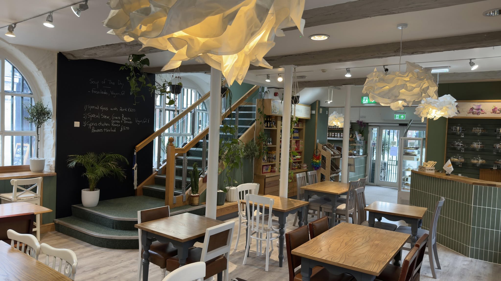 Twisted Willow cafe interior, with arched windows, wooden tables, sculptural pendant lights and green counter